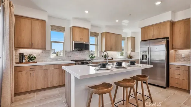 a kitchen with stainless steel appliances granite countertop a sink a stove a refrigerator cabinets and chairs