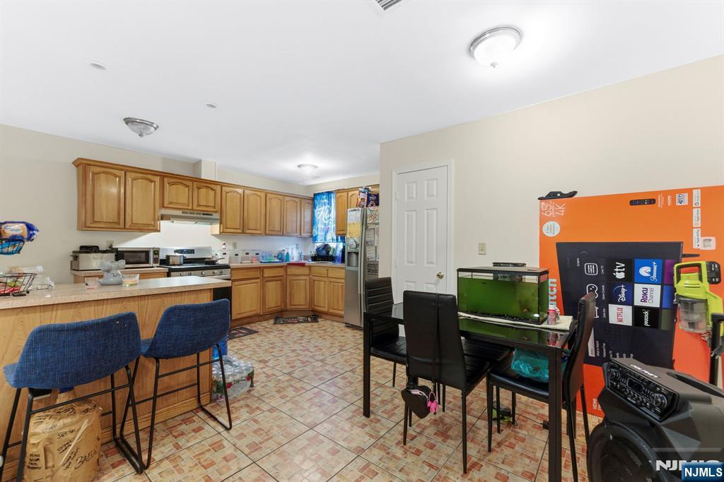 29-31 22nd Avenue Paterson, NJ 07513 - Photo 3 of 20 a kitchen with stainless steel appliances kitchen island granite countertop a table and chairs in it