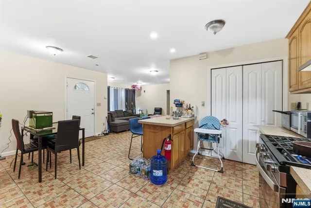 a kitchen with stainless steel appliances granite countertop a stove top oven a dining table and chairs with the wooden floor