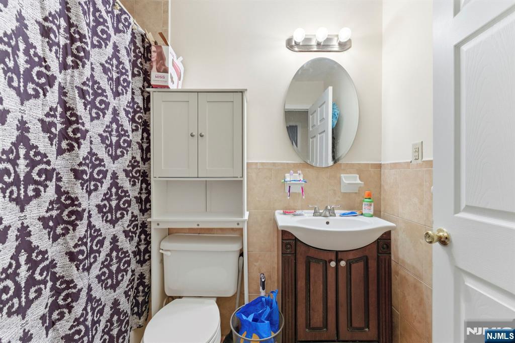 29-31 22nd Avenue Paterson, NJ 07513 - Photo 10 of 20 a bathroom with a sink and a mirror with toilet