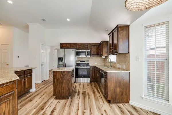 a kitchen with granite countertop a refrigerator stove top oven and sink