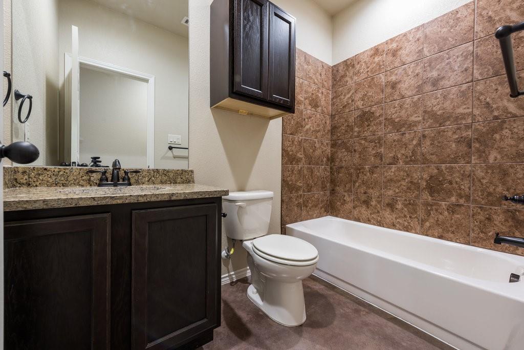 491 Jack Rabbit Lane, Unit A Buda, TX 78610 - Photo 15 of 22 Granite counters complement the rich cabinetry in this well-appointed bathroom with a spacious tub.