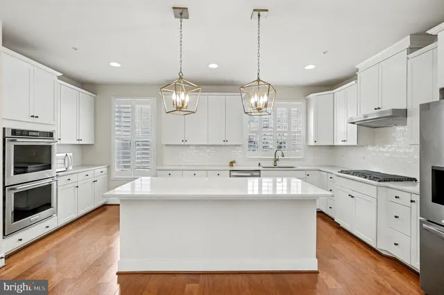 a large kitchen with kitchen island white cabinets stainless steel appliances and a chandelier