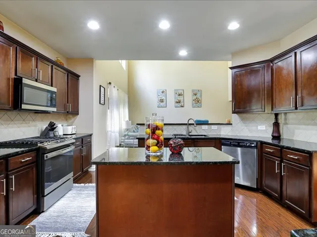 a kitchen with stainless steel appliances granite countertop a sink stove and wooden cabinets