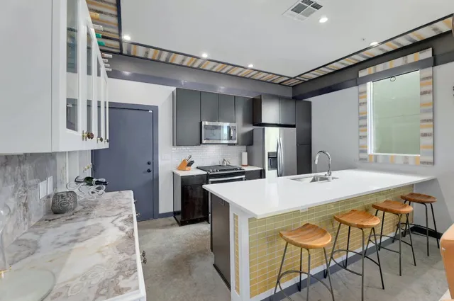 a kitchen with stainless steel appliances kitchen island granite countertop a table chairs sink and cabinets