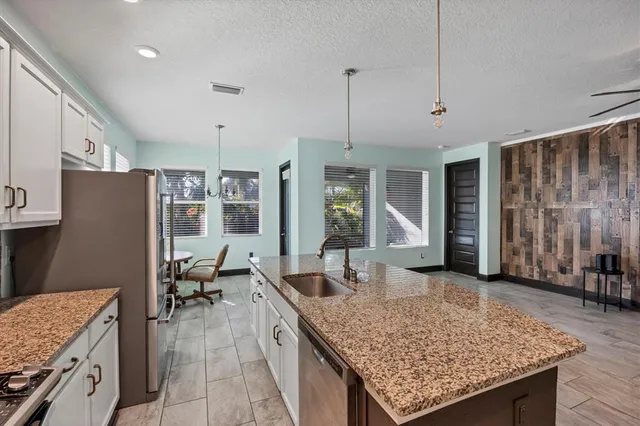a large kitchen with stainless steel appliances kitchen island granite countertop a sink a stove and a refrigerator
