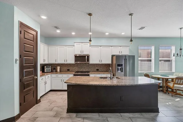 a kitchen with kitchen island a refrigerator a sink and cabinets