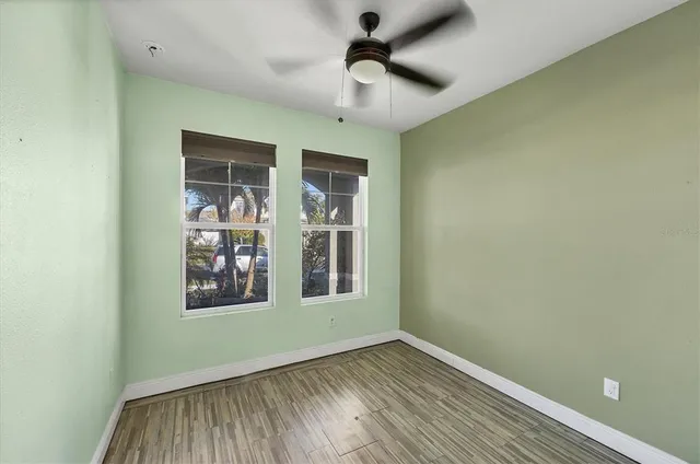 an empty room with wooden floor closet and windows