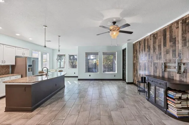 a large living room with stainless steel appliances kitchen island granite countertop furniture a fireplace and a chandelier