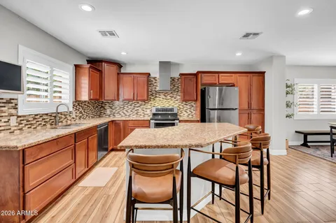 a kitchen with stainless steel appliances kitchen island granite countertop wooden cabinets a stove top oven and granite counter tops