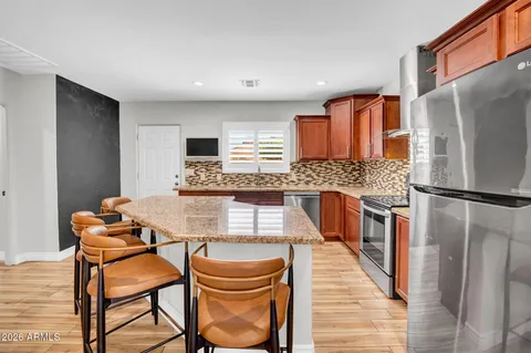 a kitchen with stainless steel appliances granite countertop a table chairs in it and wooden floors