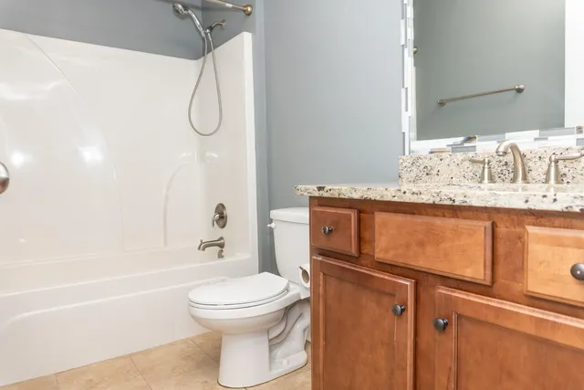 a bathroom with a granite countertop sink a toilet and shower