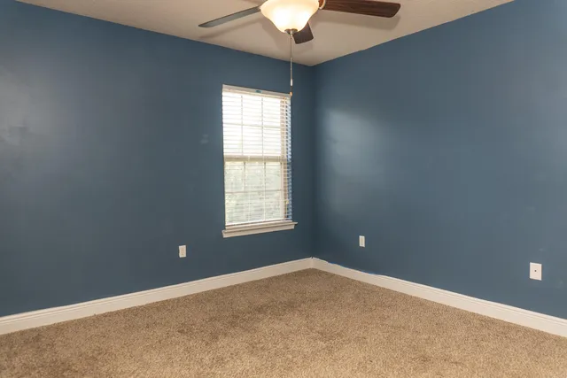 an empty room with a window and a chandelier fan