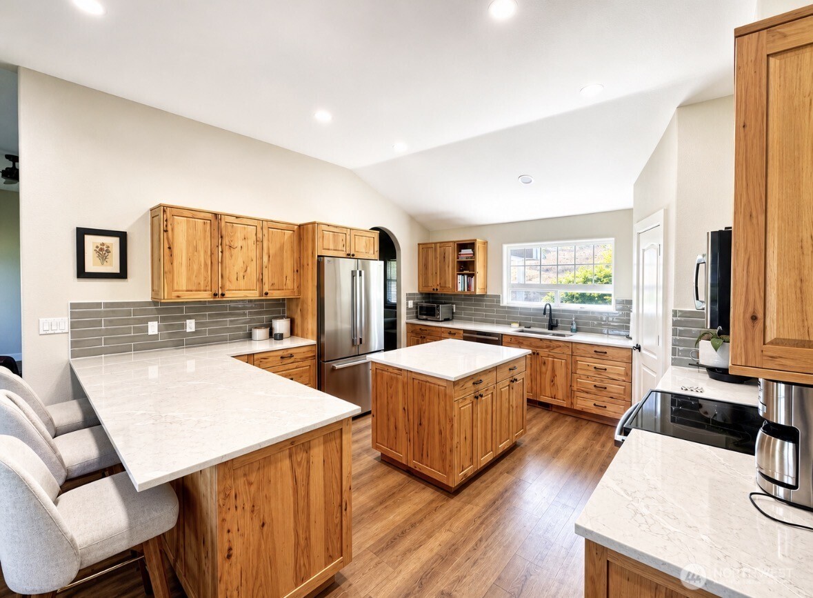 22 Rooster Flats Road Oroville, WA 98844 - Photo 13 of 28 a large kitchen with stainless steel appliances kitchen island granite countertop a large kitchen island a stove a sink dishwasher and white cabinets with wooden floor
