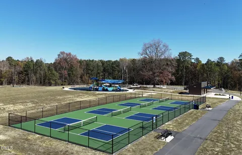 a view of swimming pool with lawn chairs and large trees