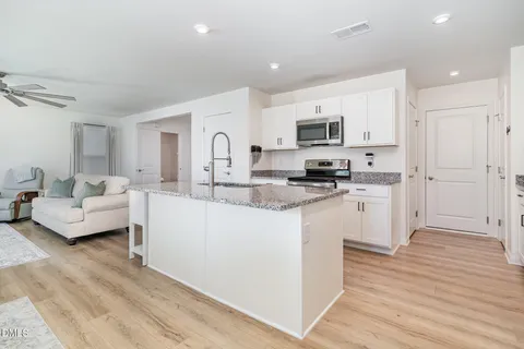 a living room with stainless steel appliances kitchen island granite countertop a stove and a sink
