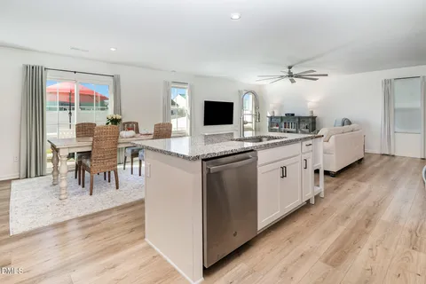 a kitchen with a sink and white cabinets with wooden floor