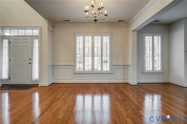 an empty room with chandelier fan and windows