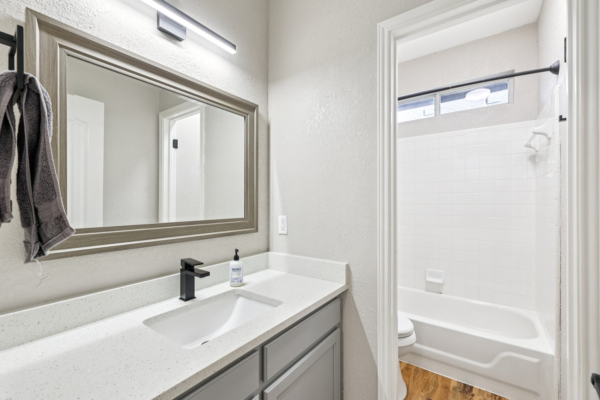 12717 Machete Trail Austin, TX 78729 - Photo 11 of 32 Bathroom with vanity, shower / washtub combination, a textured wall, and wood finished floors
