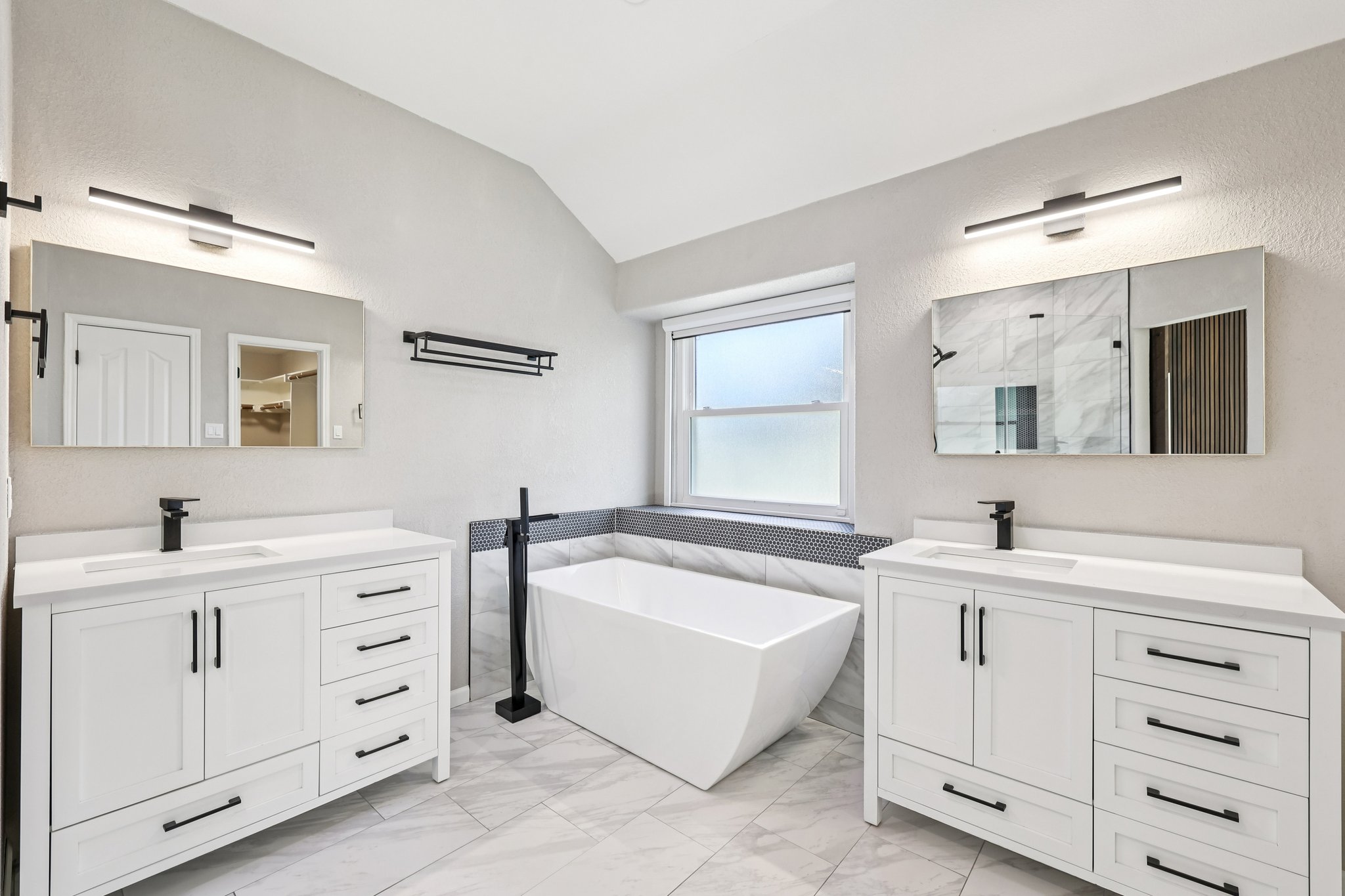 12717 Machete Trail Austin, TX 78729 - Photo 16 of 32 Full bath with two vanities, a marble finish shower, lofted ceiling, a soaking tub, and light marble finish floors