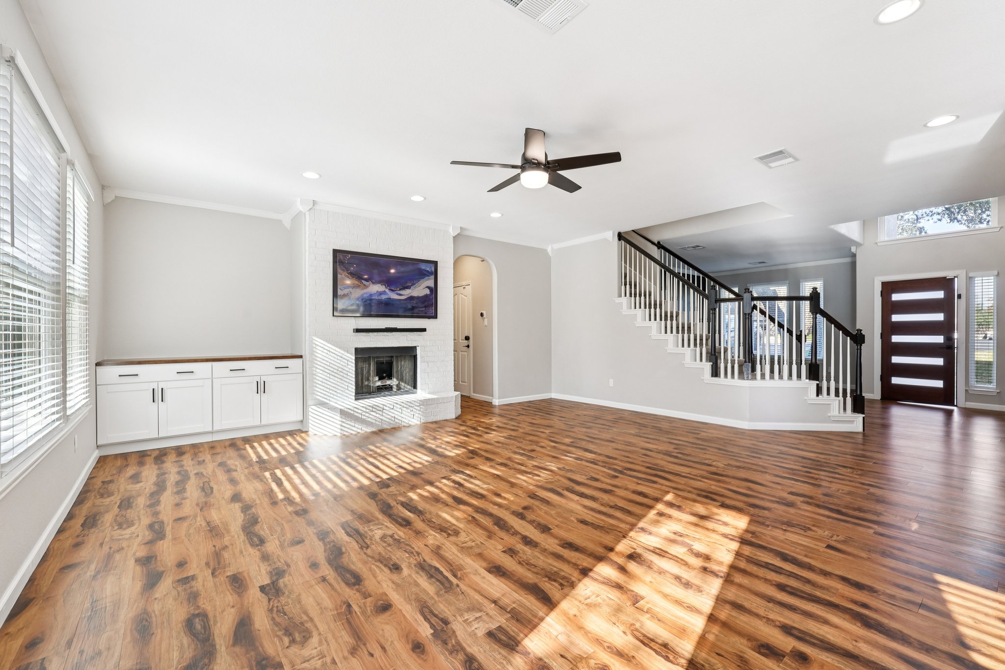 12717 Machete Trail Austin, TX 78729 - Photo 6 of 32 Unfurnished living room featuring stairway, a fireplace, ornamental molding, dark wood-style flooring, and arched walkways
