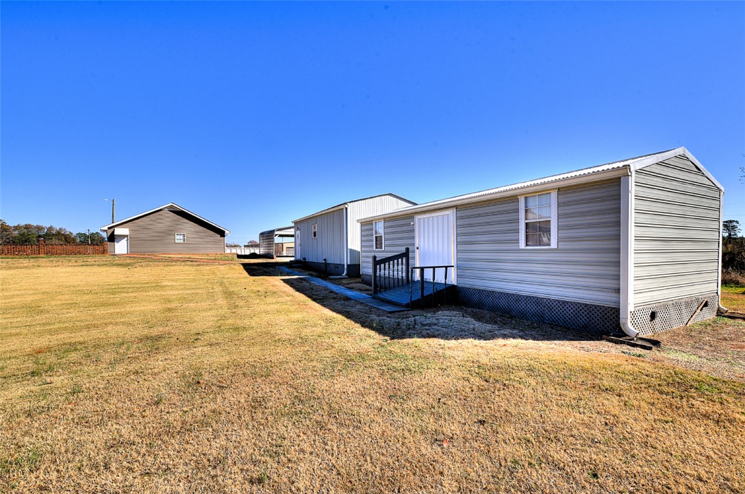 130 Raleighs Lane West Union, SC 29696 - Photo 48 of 49 A spacious grassy lawn stretches between several functional outbuildings under a clear blue sky.