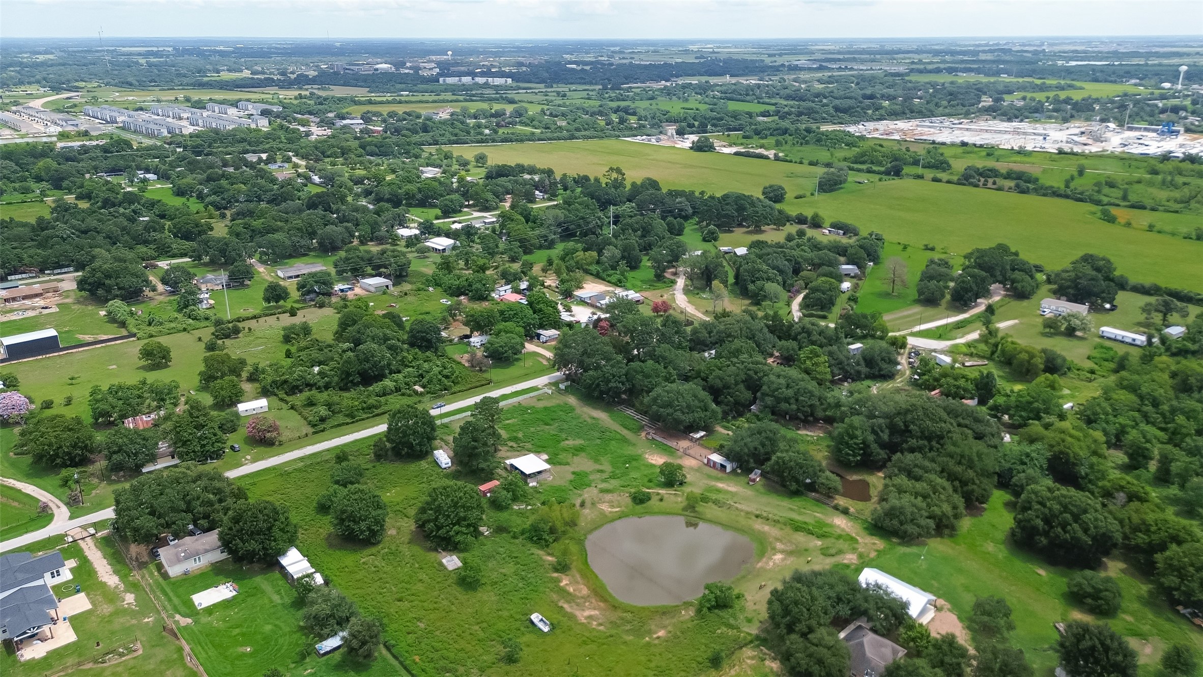 35535 Windmill Road Hempstead, TX 77445 - Photo 31 of 41 This aerial view showcases a tranquil rural landscape with scattered homes, lush greenery, and a small pond. The area offers a spacious, serene setting with easy access to nearby roads and amenities. Ideal for those seeking a peaceful countryside lifestyle.