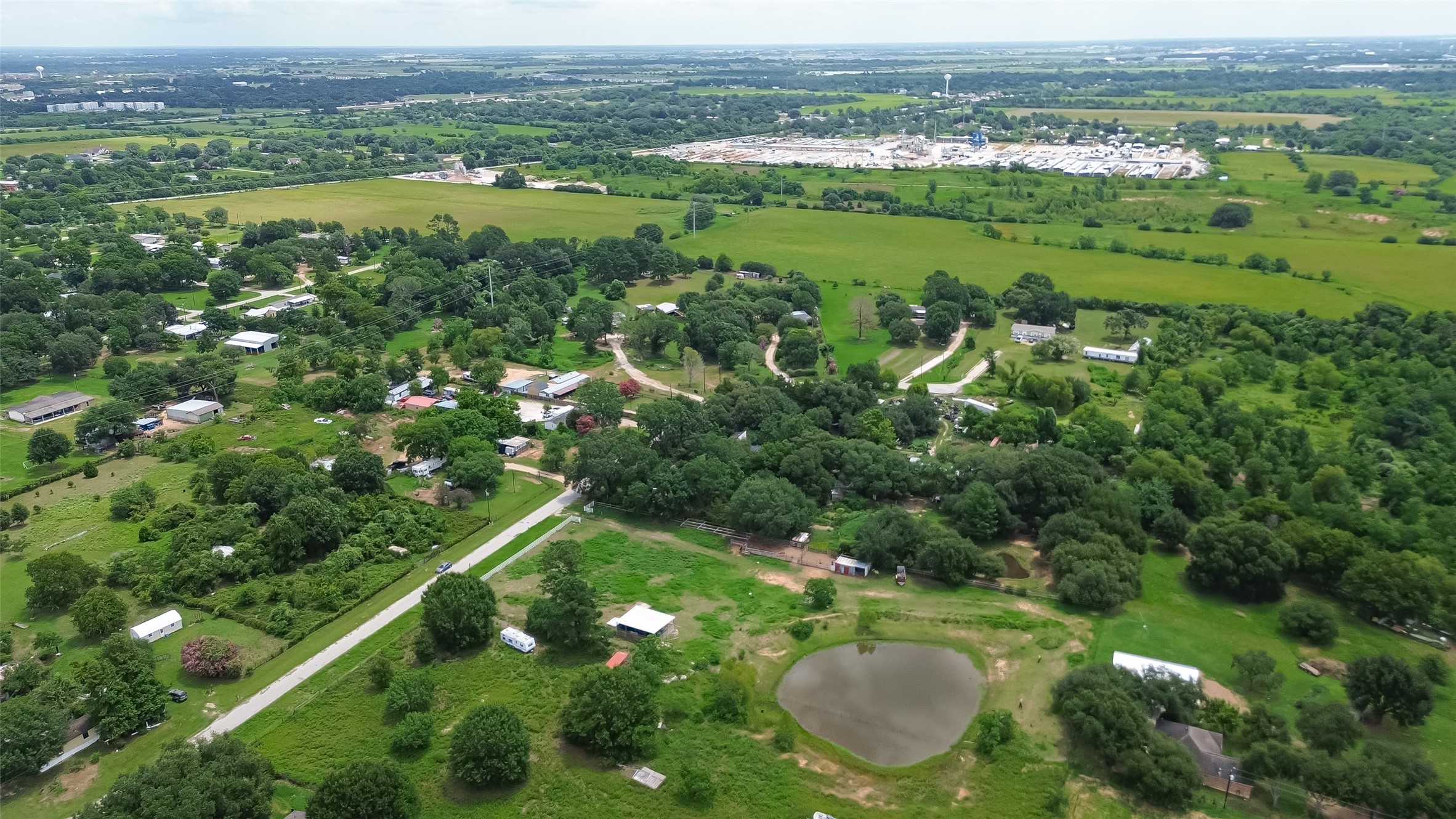 35535 Windmill Road Hempstead, TX 77445 - Photo 32 of 41 This aerial view showcases a rural area with spacious greenery, scattered homes, and a pond. The landscape features open fields, tree-lined roads, and a peaceful, country setting, ideal for those seeking tranquility and space.