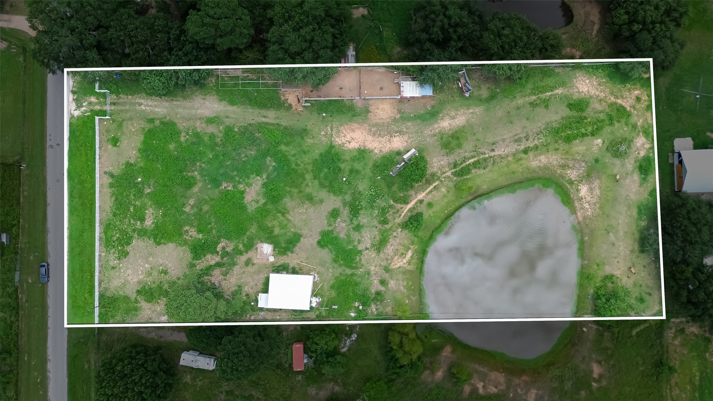 35535 Windmill Road Hempstead, TX 77445 - Photo 7 of 41 This aerial photo shows a spacious rectangular property featuring a mix of grassy areas and a small pond. The land is mostly open with some trees along the edges, offering potential for development or landscaping.