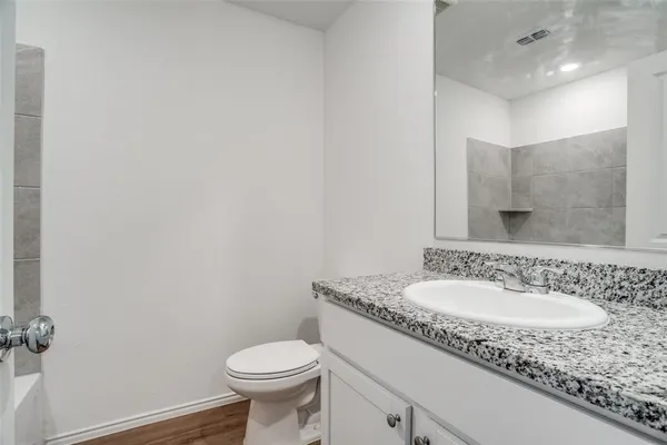 a bathroom with a granite countertop sink a toilet and a mirror