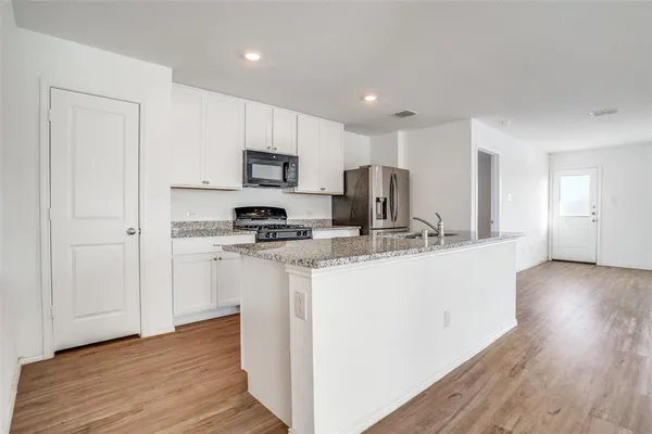 a kitchen with kitchen island granite countertop a sink cabinets and wooden floor