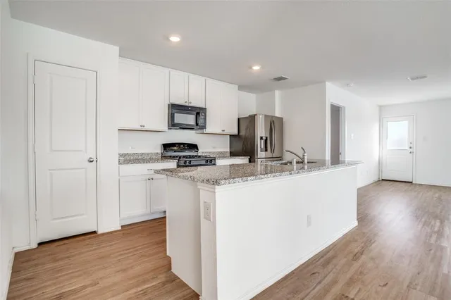 a kitchen with kitchen island granite countertop a sink cabinets and wooden floor