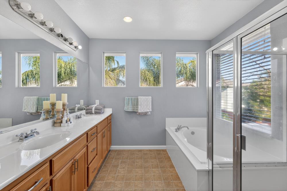 3045 Delta Tule Way Sacramento, CA 95834 - Photo 31 of 65 a spacious bathroom with a double vanity sink a large mirror a bathtub and next to a window