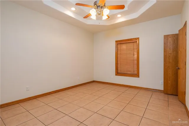 an empty room with a chandelier fan and windows
