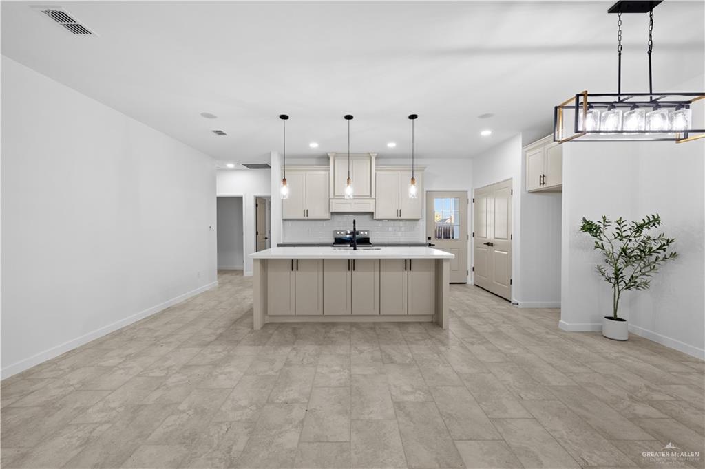 2713 East Comal Road Edinburg, TX 78542 - Photo 9 of 29 a large white kitchen with kitchen island a sink a stove a refrigerator and cabinets
