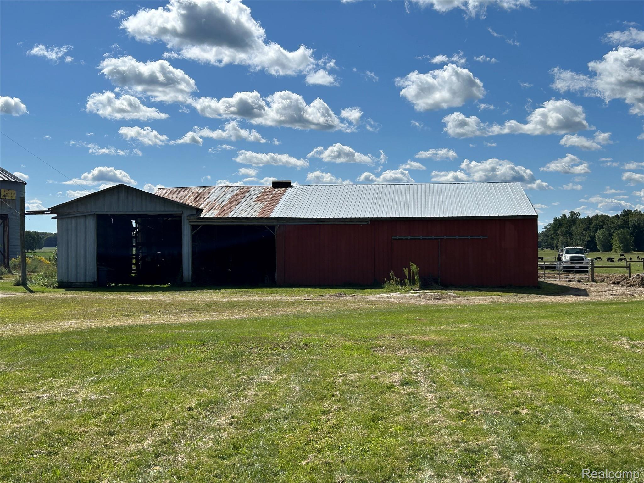 16465 Almont Road Allenton, MI 48002 - Photo 32 of 35 Red barn structure with a metal roof and an attached open-sided shed with a gable roof