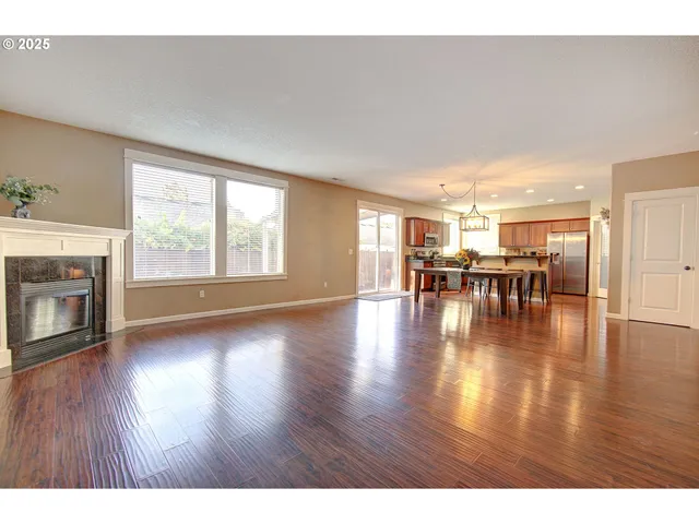 a view of an empty room with wooden floor and a fireplace