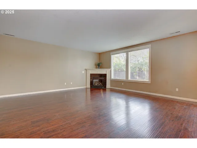 a view of empty room with wooden floor and fireplace