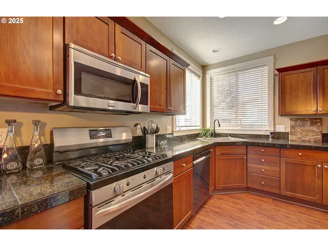 a kitchen with stainless steel appliances granite countertop a stove microwave and sink