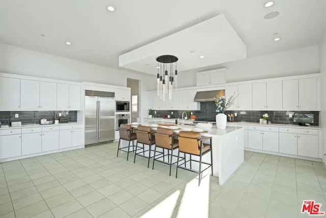 a kitchen with refrigerator a stove and chairs