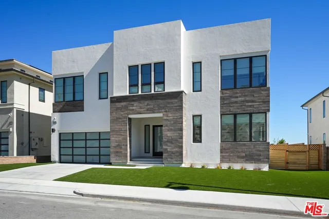 a view of a white house with a yard and large windows