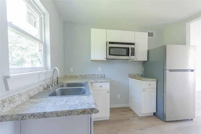 a kitchen with a sink a microwave a refrigerator and cabinets
