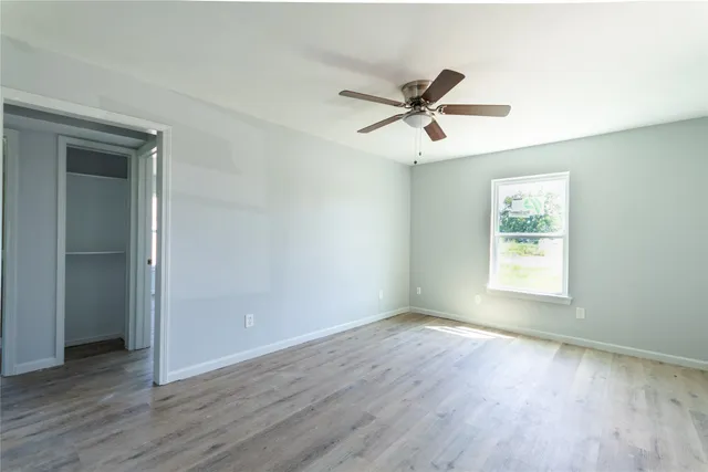 a view of empty room with wooden floor and fan
