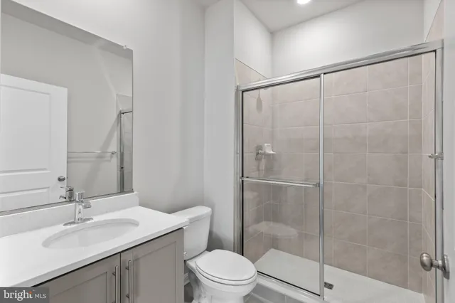 a bathroom with a shower sink vanity mirror and toilet