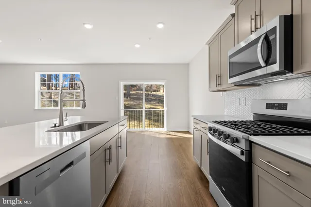 a kitchen with stainless steel appliances granite countertop a sink a stove a microwave and wooden cabinets