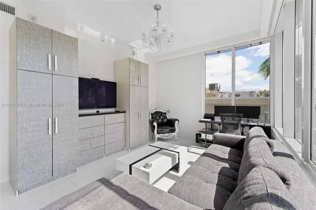 a living room with furniture a flat screen tv and a chandelier