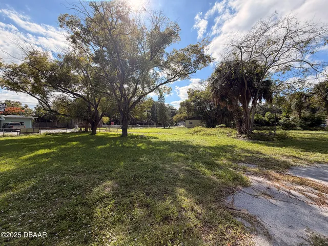 a view of grassy field with benches and trees all around