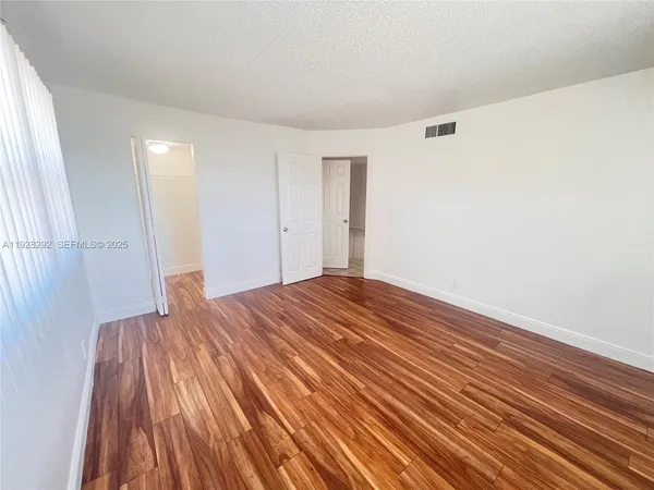 a view of empty room with wooden floor