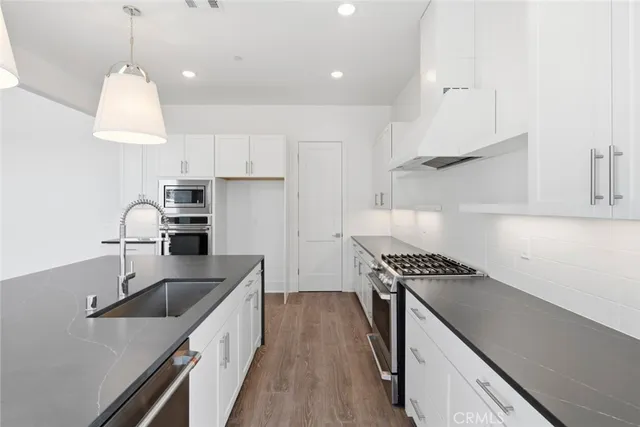 a kitchen with stainless steel appliances granite countertop a sink a stove and a refrigerator