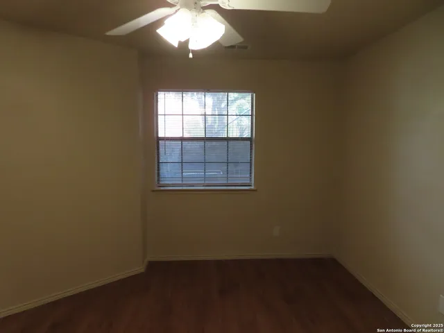 an empty room with a ceiling fan and a wooden floor